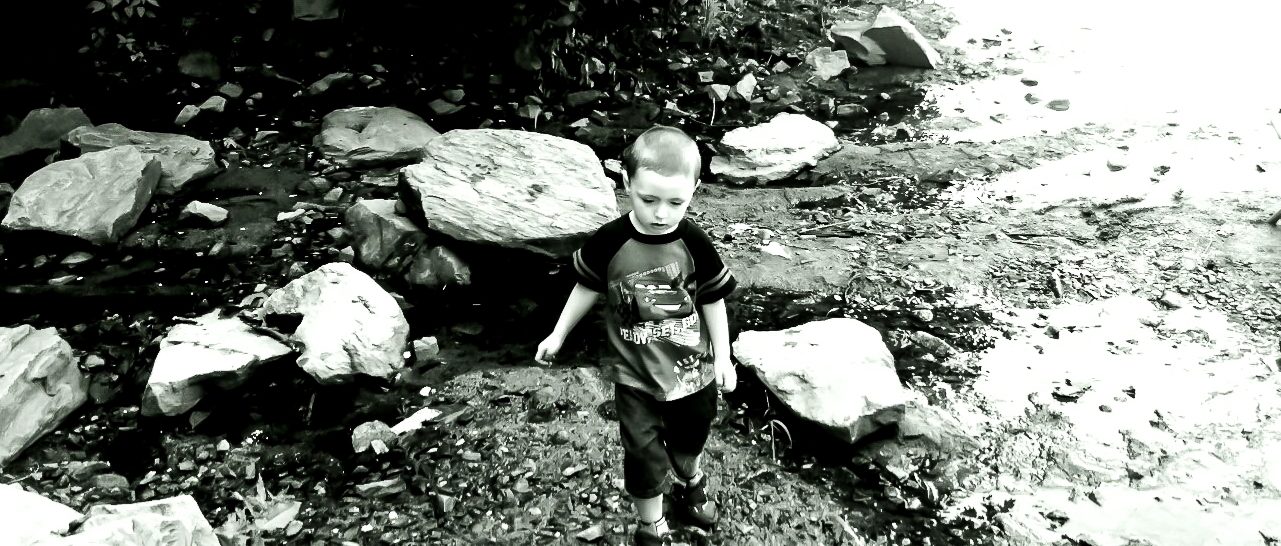 young boy crossing rocks in a river