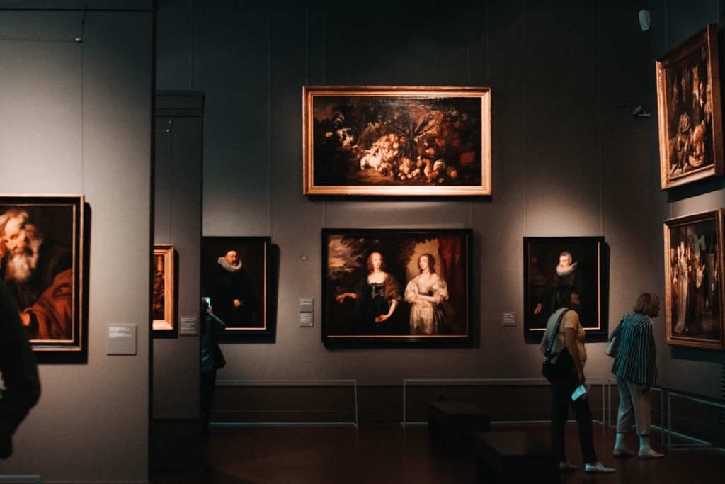 a dimly lit art gallery with black walls and classical paintings with gold frames
